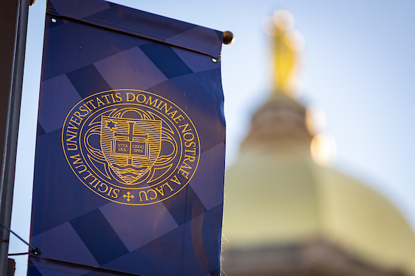 A blue banner with the University seal. The dome and Mary are in the background